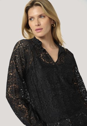 Black lace blouse featuring a ruffled collar, intricate floral patterns, long sleeves, and a relaxed fit, showcasing a textured design.