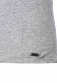 Graues T-Shirt mit kurzen Ärmeln aus einer Baumwollmischung, mit einer dezenten Textur und einem kleinen Metalletikett mit der Aufschrift "KEYLARGO" in der Nähe des Saums.