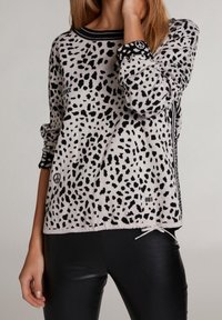 Jasnoszara bluza z czarnym wzorem w kropki. Posiada okrągły dekolt, prążkowane mankiety oraz sznurek w dolnej części.