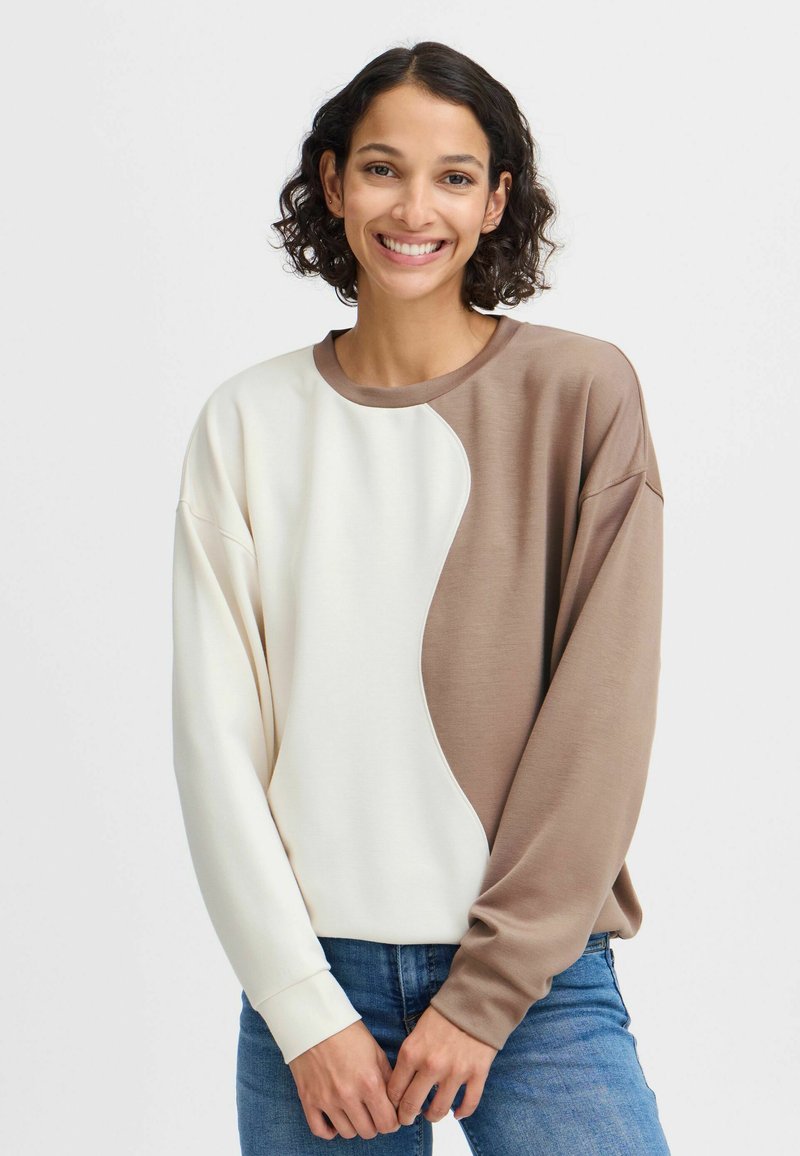 Sweat-shirt surdimensionné en crème et marron avec un design courbé. Fabriqué en tissu doux, avec des poignets côtelés et un col rond.