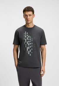 Grå bomulls t-shirt med en geometrisk grafisk design i ljusblått och gult, korta ärmar och rund halsringning.