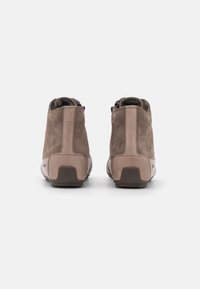 Bottines en suède marron avec une finition lisse, présentant un panneau arrière contrastant, un talon texturé et une semelle en caoutchouc pour une meilleure adhérence.