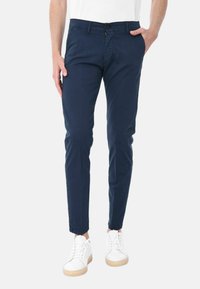 Pantaloni di cotone blu navy con vestibilità slim, design classico a cinque tasche, chiusura con bottone e texture sottile, abbinati a sneakers bianche.