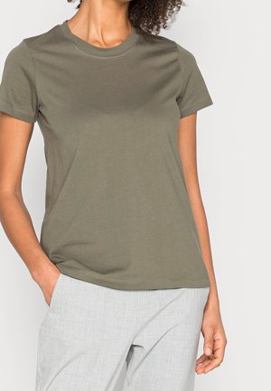 Olivengrünes T-Shirt mit kurzen Ärmeln aus weichem Stoff, mit klassischem Rundhalsausschnitt und dezenten Nahtdetails. Kombiniert mit hellgrauen Hosen.