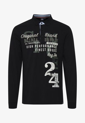 Must mustakateedega polo särk, millel on valge kaelus, tekstureeritud kangas, suured graafilised printimised ja segatud tüpograafia kontrastsetes värvides.