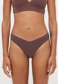Parte inferior de bikini marrón con una cinturilla en forma de V, hecha de un material suave y elástico. Diseño minimalista sin patrones ni adornos.