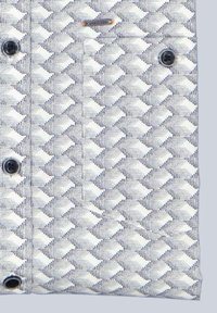 Texturiertes Hemd aus Stoff mit einem geometrischen weißen und marineblauen Muster, ausgestattet mit schwarzen Knöpfen und einem kleinen Metallakzent nahe dem oberen Bereich.