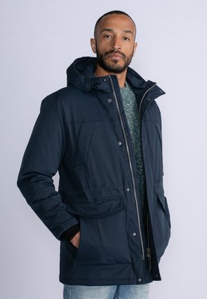 Parka acolchada de color azul marino con capucha, cierre de cremallera en el frente, múltiples bolsillos y una textura suave. Presenta un diseño sólido para brindar calor.