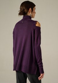 Maglione oversize viola a maglia con colletto alto, dettagli sulle spalle a taglio e orlo a coste. Trama liscia, vestibilità casual e maniche lunghe.