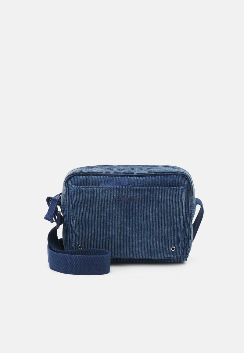 Pequeña bolsa de hombro de pana azul con bolsillo frontal, correa ajustable y logotipo "LOIS" bordado en la parte frontal.