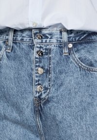 Svetle modré džíny z denimu s vysokým pasem, pěti knoflíky vepředu a jemnou vybledlou strukturou. Klasický design se zpevněným šitím a kapsami.