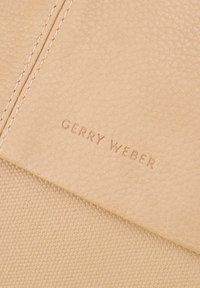Texture in pelle beige con una lieve grana nella parte superiore e tessuto intrecciato nella parte inferiore; dettaglio goffrato "GERRY WEBER".