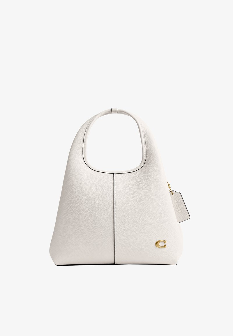 Sac à main en cuir blanc texturé avec une poignée supérieure incurvée, logo doré "C" en bas à droite, et une étiquette attachée à la fermeture éclair latérale.