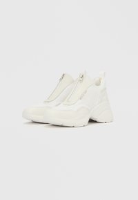 Weiße Sneakers mit Reißverschluss vorne, aus Mesh- und Synthetikmaterialien, mit abgerundeter Spitze, strukturierten Akzenten und einer gepolsterten Sohle.