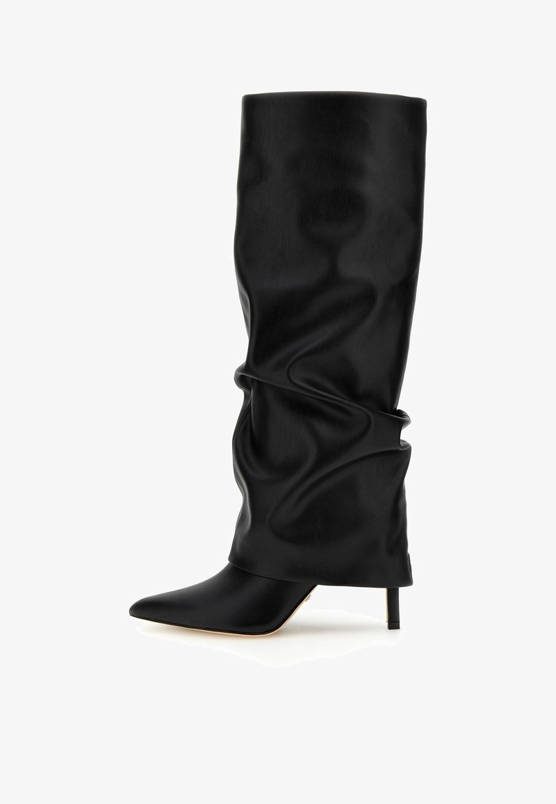 Botte noire haute jusqu'au genou, à talon haut ample, avec un bout pointu et un talon aiguille fin sur fond blanc.