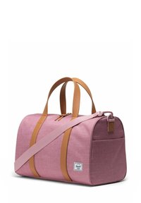 Sac de sport rose avec des poignées en cuir marron et une bandoulière réglable, doté d'une fermeture éclair et d'une petite poche sur le côté.