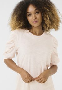 T-shirt in rosa chiaro con maniche corte a sbuffo e scollatura rotonda. Tessuto morbido e testurizzato con una vestibilità comoda.