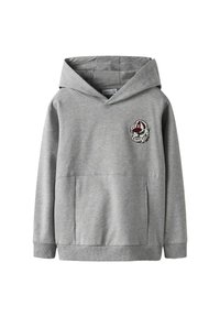Sudadera con capucha gris, con un bolsillo frontal, escote en V y un parche decorativo que presenta la cara de un personaje en el lado izquierdo. Textura de tela suave.