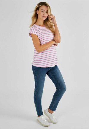Top a righe rosa e bianche a maniche corte, abbinato a jeans skinny blu e sneakers bianche. Il top presenta maniche arrotolate e una vestibilità ampia.