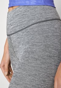 Grå träningstights med en texturerad, melerad mönstring. Har en hög midja och en åtsittande design för komfort och flexibilitet.