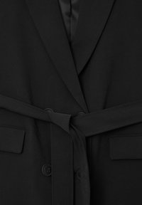 Schwarzer Mantel mit Gürtel, Reverskragen, zwei frontalen Taschen, strukturiertem Stoff und Knopfverschlüssen. Minimalistisches Design mit glattem Innenfutter.