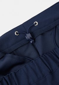 Marineblauwe elastische tailleband met verstelbare trekkoord en plastic toggle op een paar broeken of shorts.