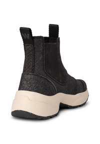 Botas chelsea negras con tela brillante, paneles laterales texturizados y suela gruesa beige. Tirador robusto para facilitar el calzado.