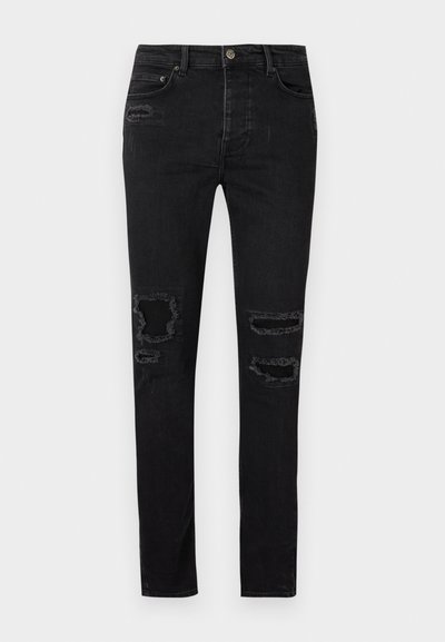 Jeans de mezclilla negra con corte slim, que presentan desgarros desgastados en las rodillas, costuras tonales y un cierre clásico de botón y cremallera.