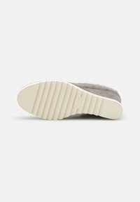 Semelle de chaussure en daim gris avec un motif texturé et strié ; semelle extérieure en caoutchouc beige clair offrant une bonne adhérence ; design minimaliste avec des lignes épurées.