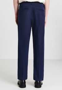 Pantaloni blu navy realizzati in tessuto morbido, con due tasche posteriori, design a gamba dritta e dettagli di cucitura minimi.