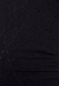 Zwart gemarmerde stof met een subtiel patroon en verheven elementen. Het materiaal lijkt zacht, met een lichte glans en delicate oppervlakdetails.