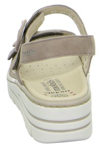 Sandalo beige con tomaia in suede testurizzato, suola in gomma, cinturino regolabile e un'accento floreale sul lato. Presenta una soletta imbottita.