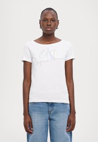 Camiseta blanca de algodón con mangas cortas y escote amplio, con el gráfico "E.A." y "Emporio Armani" en colores plateados y pastel.