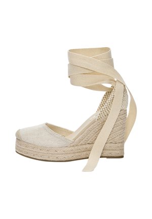 Beigen värinen kiilakorollinen espadrille, jossa punottu juuttipohja, suljettu kärki ja pitkät kangasnauhat nilkan ympärille käärittäväksi ja sidottavaksi.