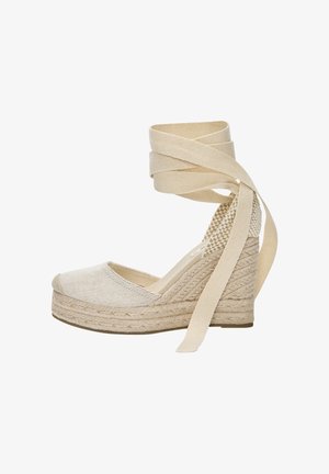 Beigen värinen kiilakorollinen espadrille, jossa punottu juuttipohja, suljettu kärki ja pitkät kangasnauhat nilkan ympärille käärittäväksi ja sidottavaksi.