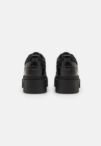 Zwarte platform sneakers met een gladde, glanzende afwerking. Chunky zool en gewatteerde kraag, met een vetersluiting en verstevigde stiksels.
