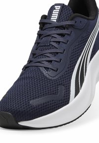 Baskets de sport bleu foncé avec un dessus en mesh, lacets plats et accents blancs. Elles présentent une semelle épaisse et texturée ainsi qu'un logo PUMA sur la languette.