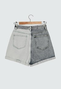 Farkkushortsit, joissa on kaksivärinen muotoilu: vaaleanharmaa toisella puolella ja tummanharmaa toisella, risaiset lahkeet ja takataskut.