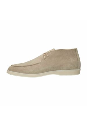 Beigefarbene Wildleder-Stiefeletten mit runder Zehenpartie, genähten Details, flacher Gummisohle und zwei dezenten Schnürsenkeln für den Verschluss.