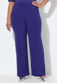 Pantalones de pierna ancha morados hechos de una tela suave con una cintura alta; combinados con tacones plateados de punta; diseño simple, sin patrones visibles.