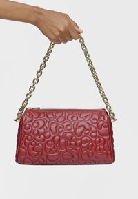 Czerwona skórzana torba na ramię z tłoczonym wzorem z wirowaniem, wyposażona w złoty łańcuszek i zamek błyskawiczny. Kompaktowy, prostokątny kształt.