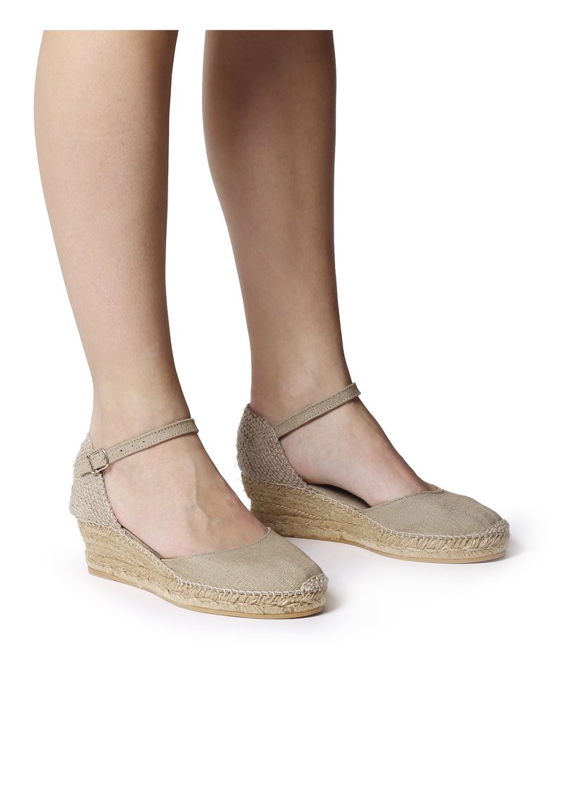 Beige espadrille wedges met een geweven jute zool, met een stoffen bovenwerk, enkelbandje en open zijkanten. Soepele textuur met gestikte details.