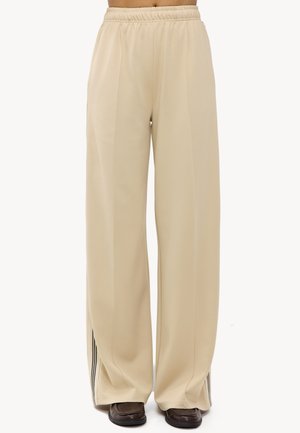 Pantalones de pierna ancha beiges con cinturilla elástica. Tejido suave con franjas laterales en contraste y aberturas en el dobladillo.