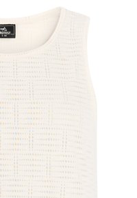 Gros plan sur un haut blanc sans manches avec un motif subtil de petits carrés et un col rond, étiquette de taille S 36 visible à l'intérieur du col.