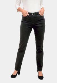 Schmale schwarze Denim-Jeans mit einer mittelhohen Taille, vorderen Taschen und einem Knopfverschluss, kombiniert mit schwarzen High Heels.