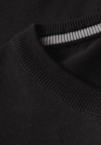 Svart tröja med en strukturerad stickning. Kragen har en ribbad rand i vitt och grått, vilket betonar en kontrasterande detalj.