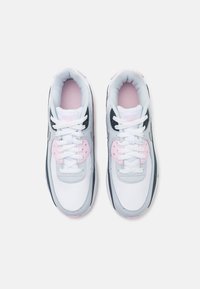 Nike tenisice s bijelim kožnim gornjim dijelom, sivi detalji i ružičasti akcenti na jeziku i vezicama. Klasični dizajn s vezicama i podstavljenim okovratnikom.