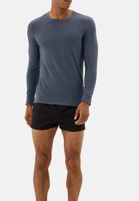 Langærmet crew neck t-shirt i mørkeblå, lavet af et blødt stof, parret med sorte shorts, der har en afslappet pasform og glat tekstur.
