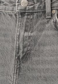 Gray denim fabric featuring a stitched waistband, front seam, and metal button. Texture appears slightly worn with creased areas.