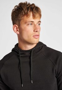 Hætte sweatshirt i mørkegrå stof med en tekstureret finish. Har raglanærmer og justerbar snor med metalspidser.